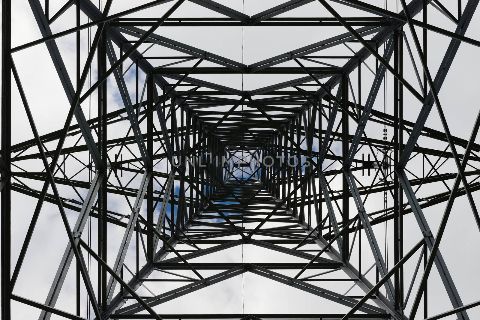 Dark abstract image of the inside of an electrical pylon. Interior skyward view, looking up, lattice structure creates an industrial themed pattern.