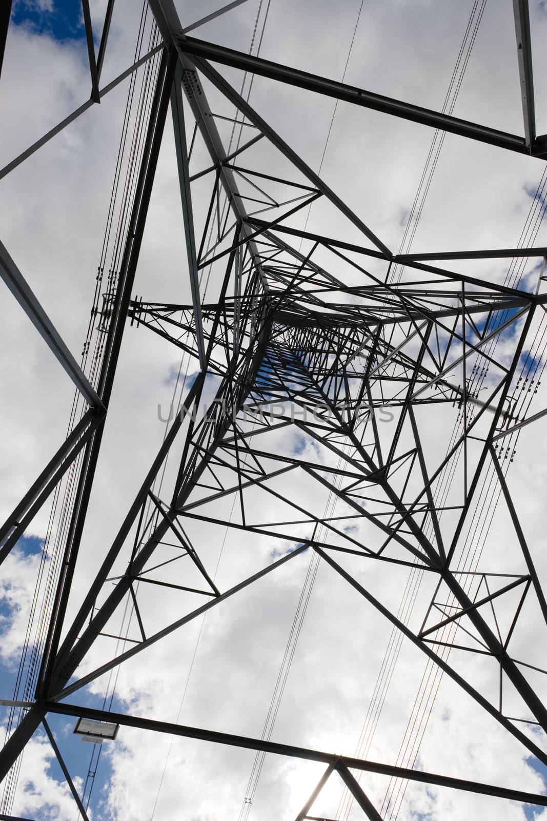 Interior corner of industrial electrical transmission pylon. Cloudy background, abstract metal pattern and unusual angle and point of view.