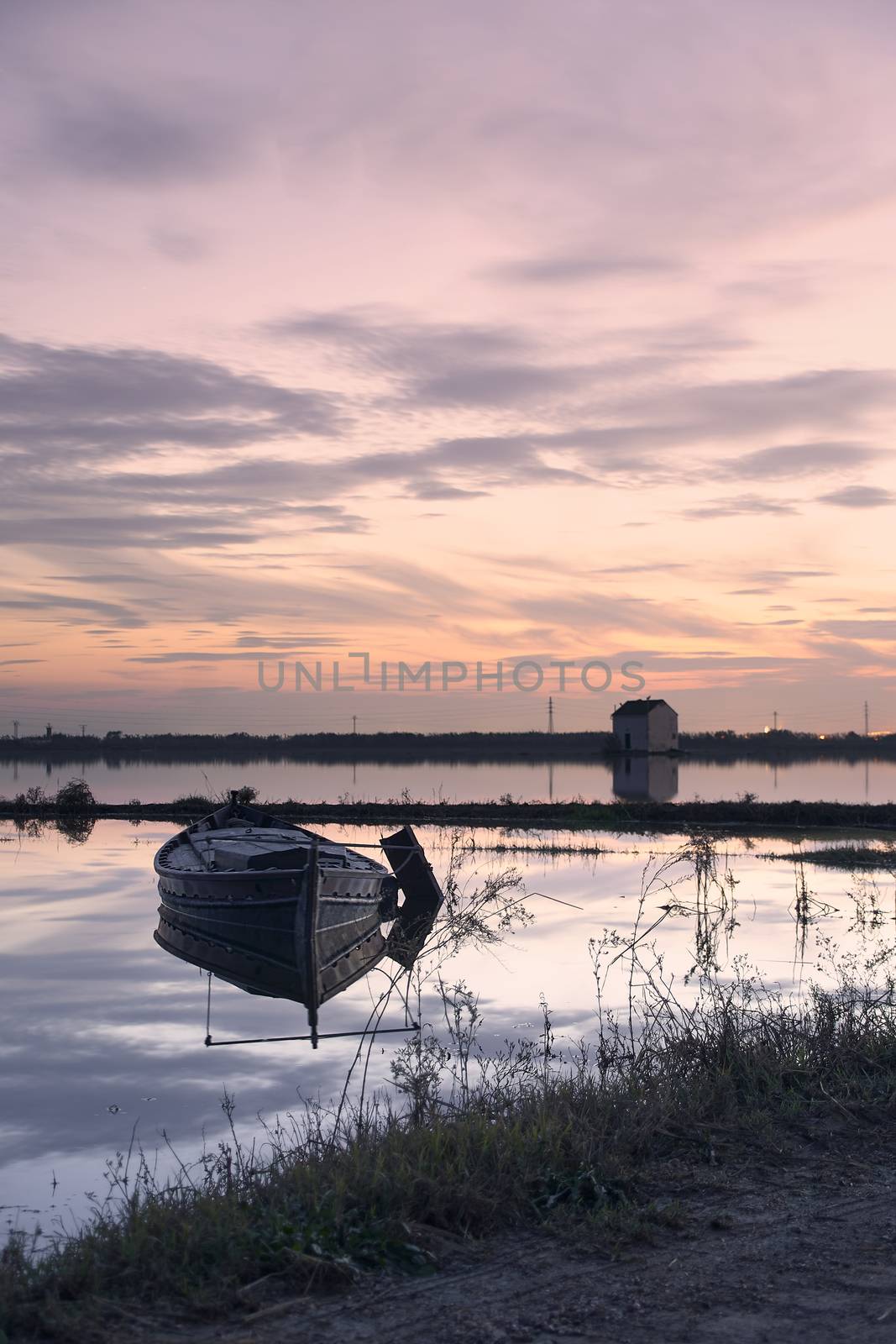 Small boat on the lake at sunset, houses, reflections, beautiful sky