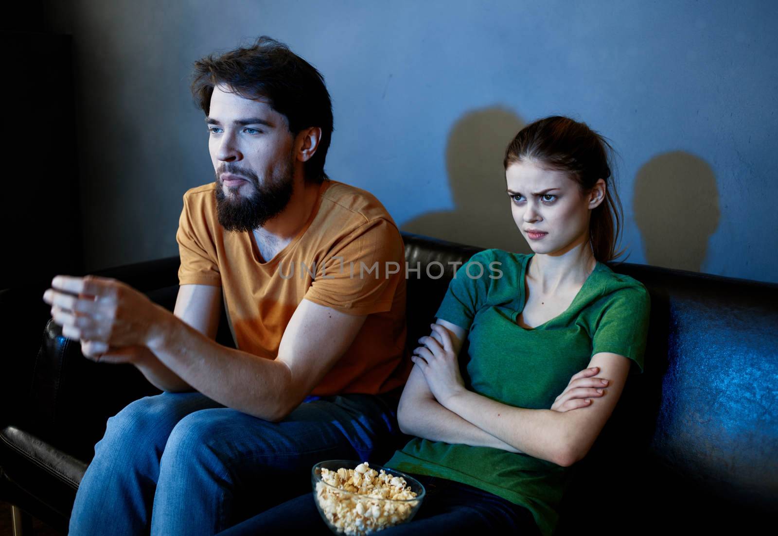 A man and a woman are watching a movie in the cinema on the sofa indoors by SHOTPRIME