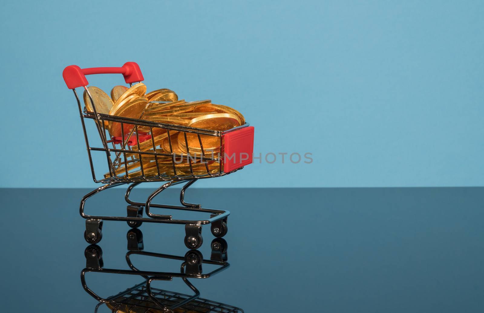 Mockup or concept background for winter sales with shopping cart filled with gold coins set against a blue background