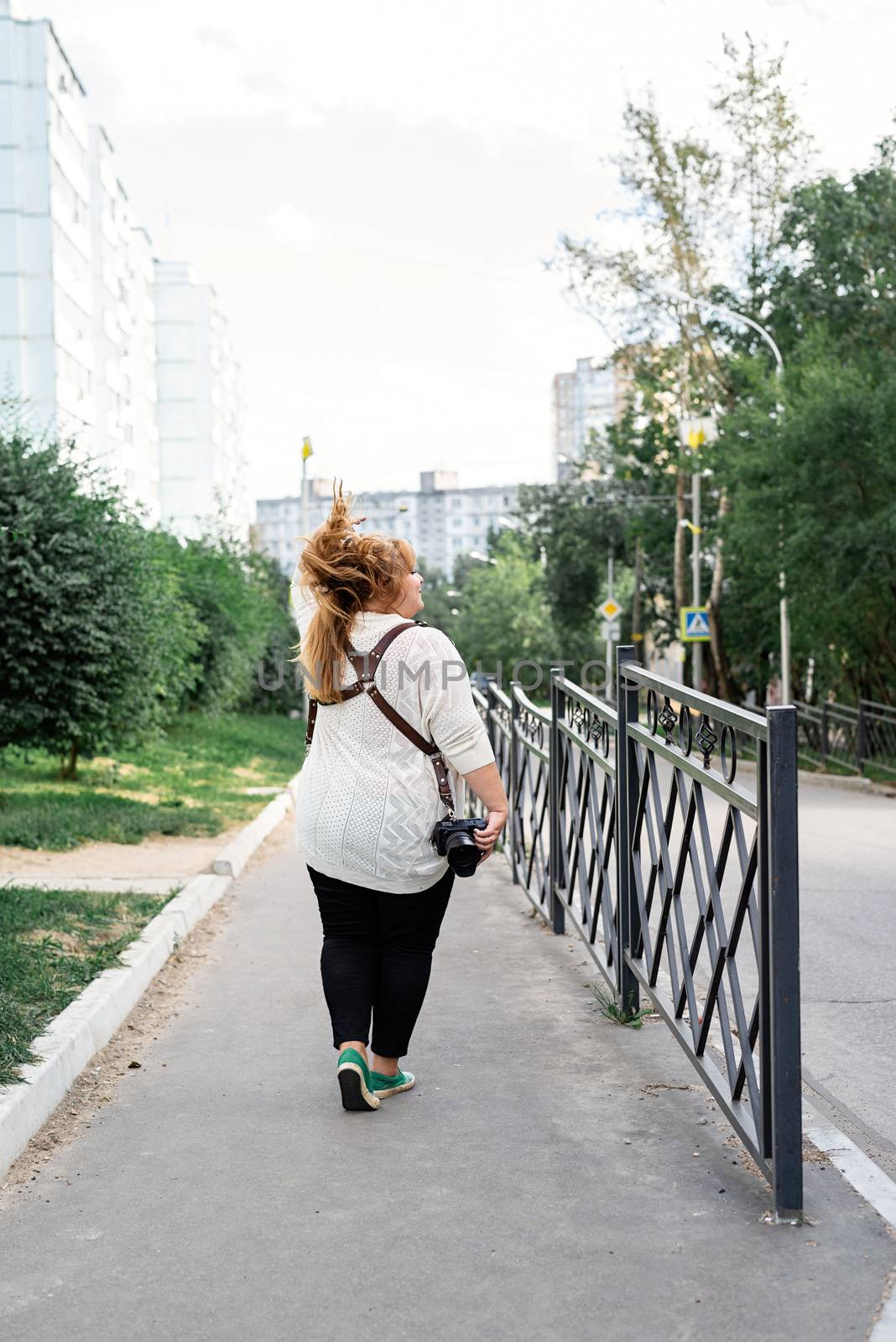 Travel, tourism and entertainment. Plus size woman photographer working at the street