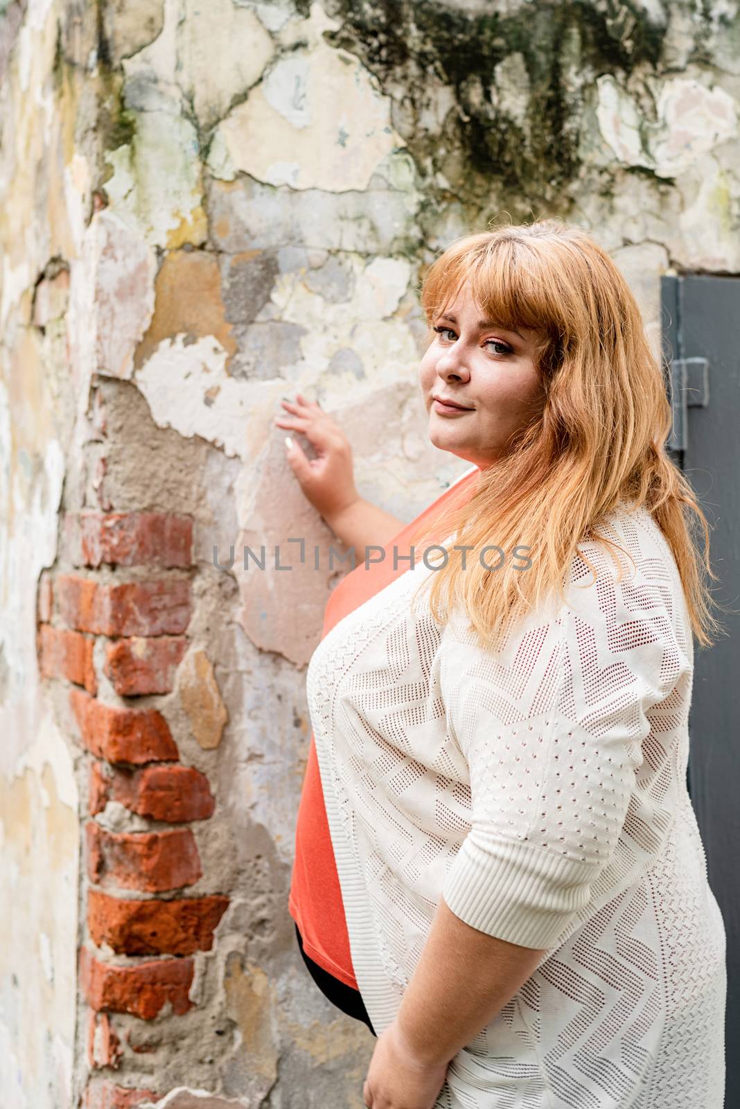 Portrait of a young beautiful caucasian plus size woman standing on the street smiling by Desperada