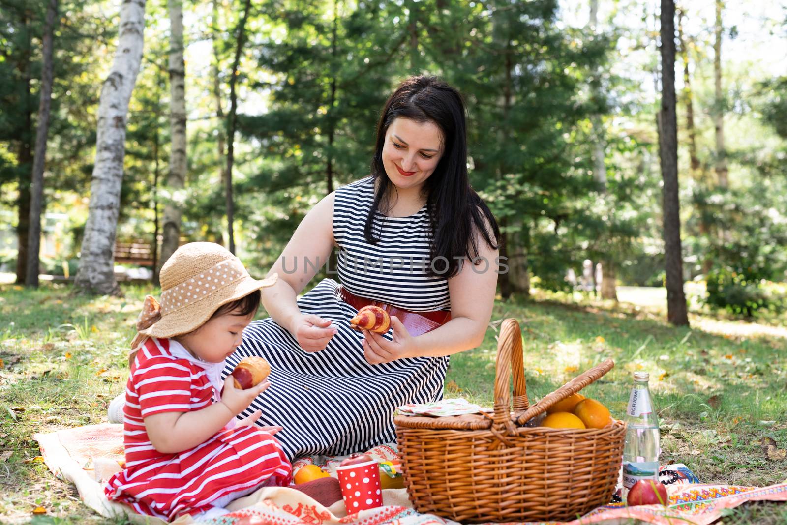 Interracial family of mother and daughter in the park having a picnic by Desperada