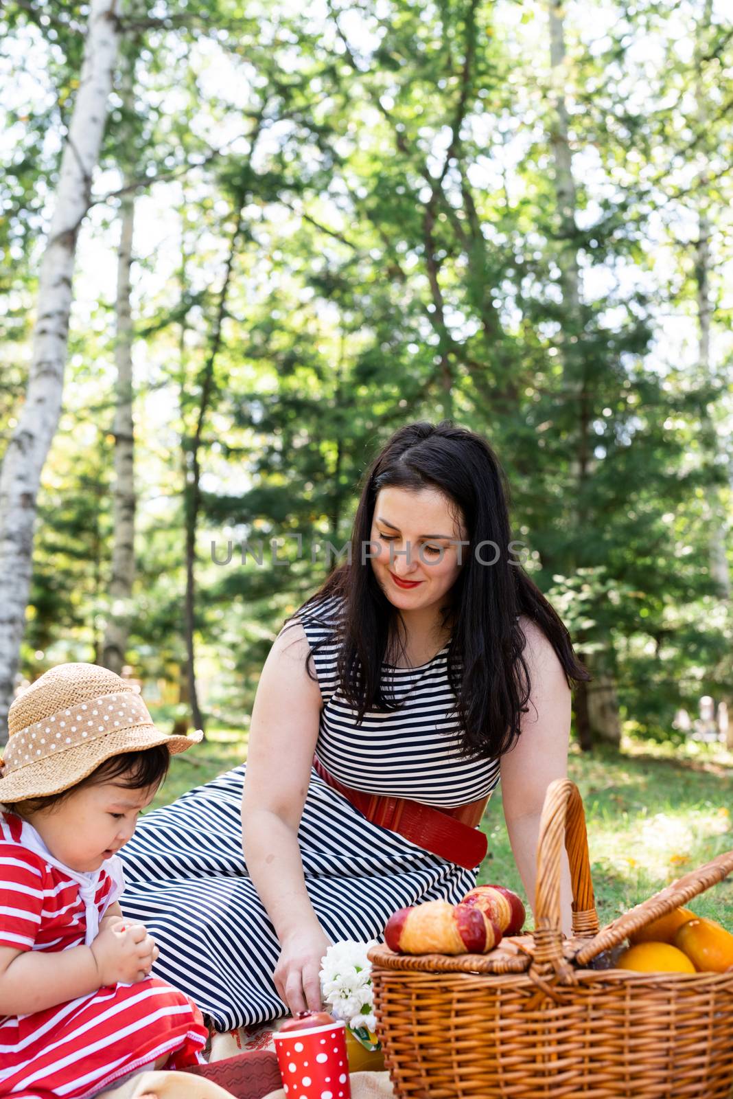 Parks and recreation. Interracial family. Interracial family of mother and daughter in the park having a picnic