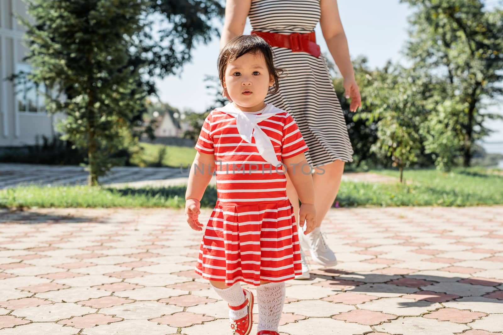 Happy multiracial family of mother and daughter walking in the park by Desperada