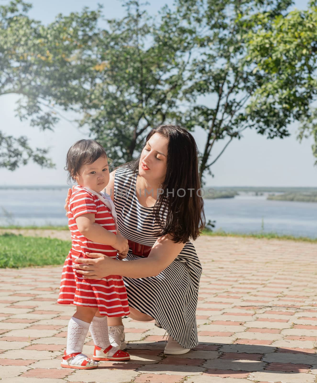 Happy multiracial family of mother and daughter walking in the park by Desperada