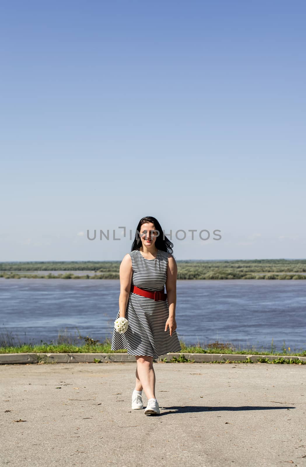 Young woman holding flowers on riverside background by Desperada