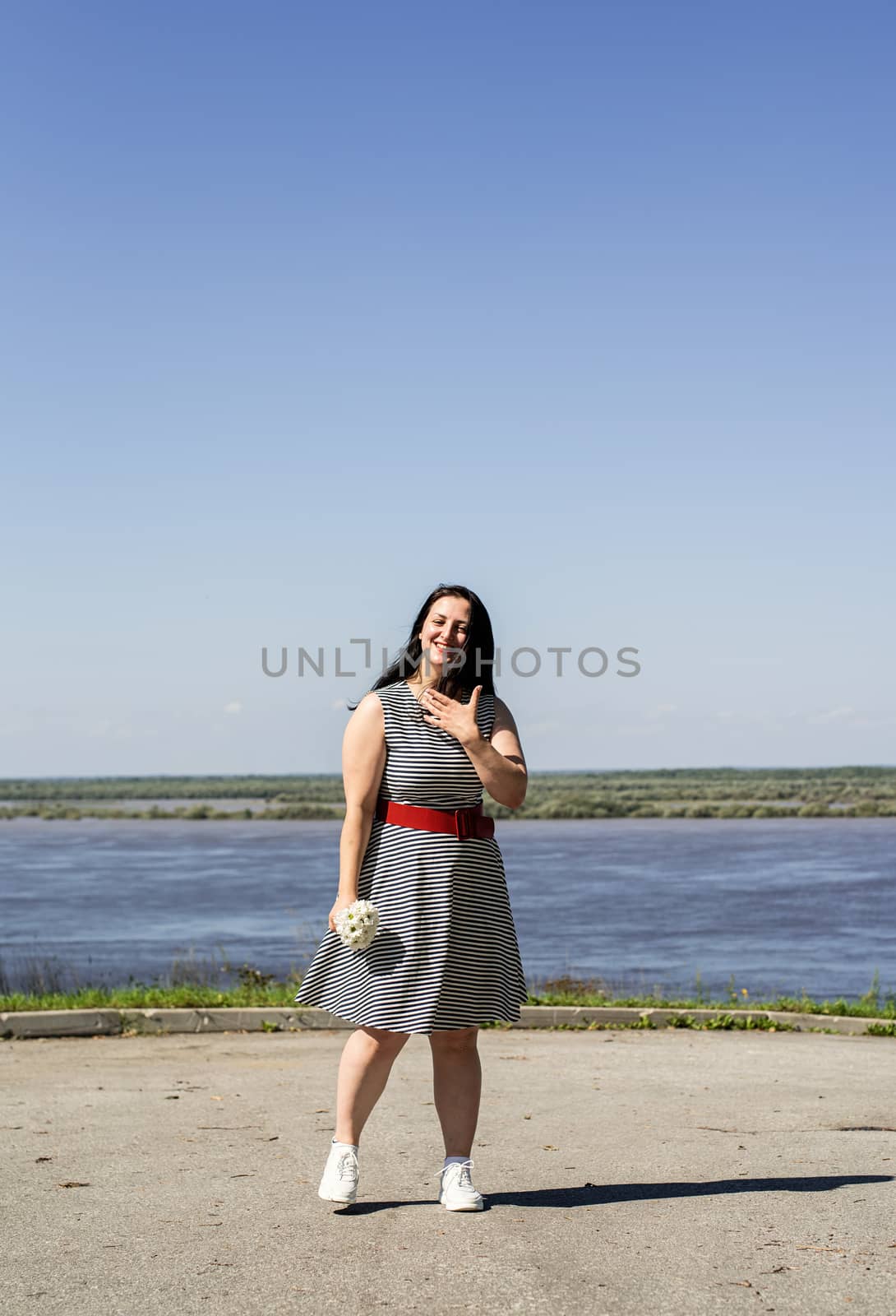 Young woman holding flowers on riverside background