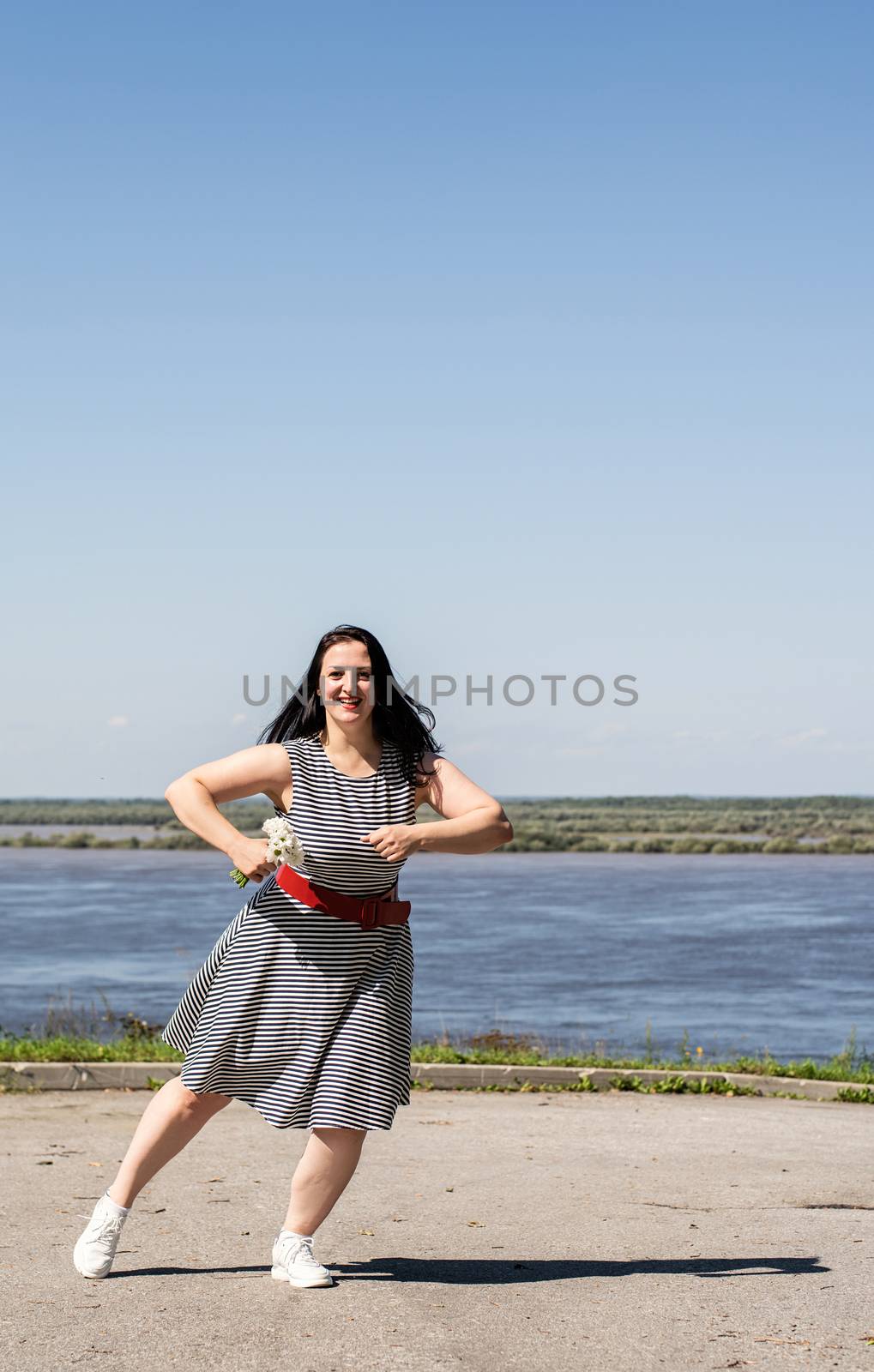 Young woman holding flowers and dancing on riverside background by Desperada