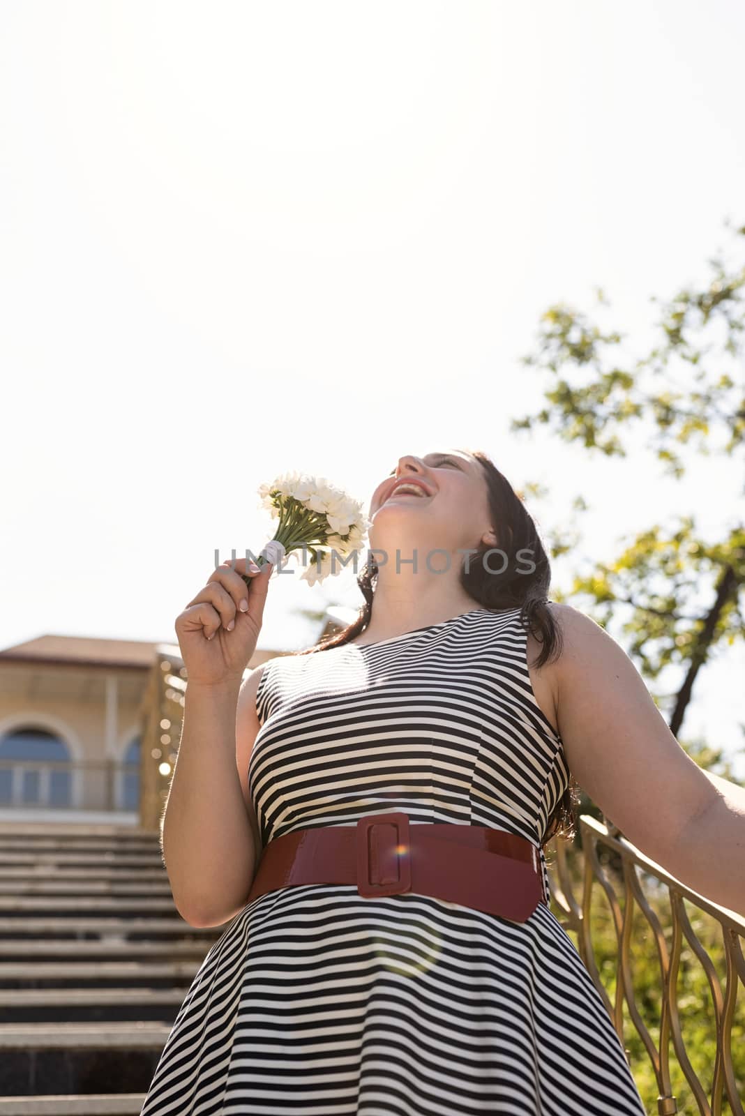 Portrait of laughing woman holding a bouquet of flowers by Desperada