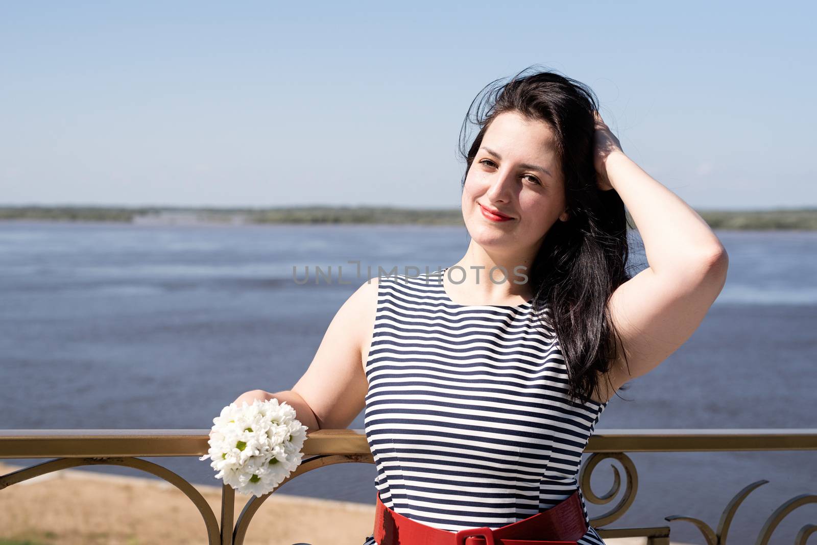 Young woman holding flowers on riverside background