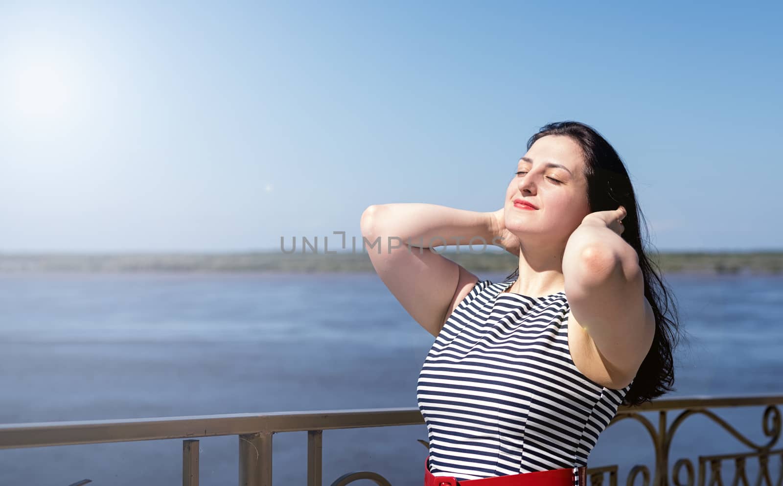 beautiful young woman standing by the riverside enjoying the view in the summer day