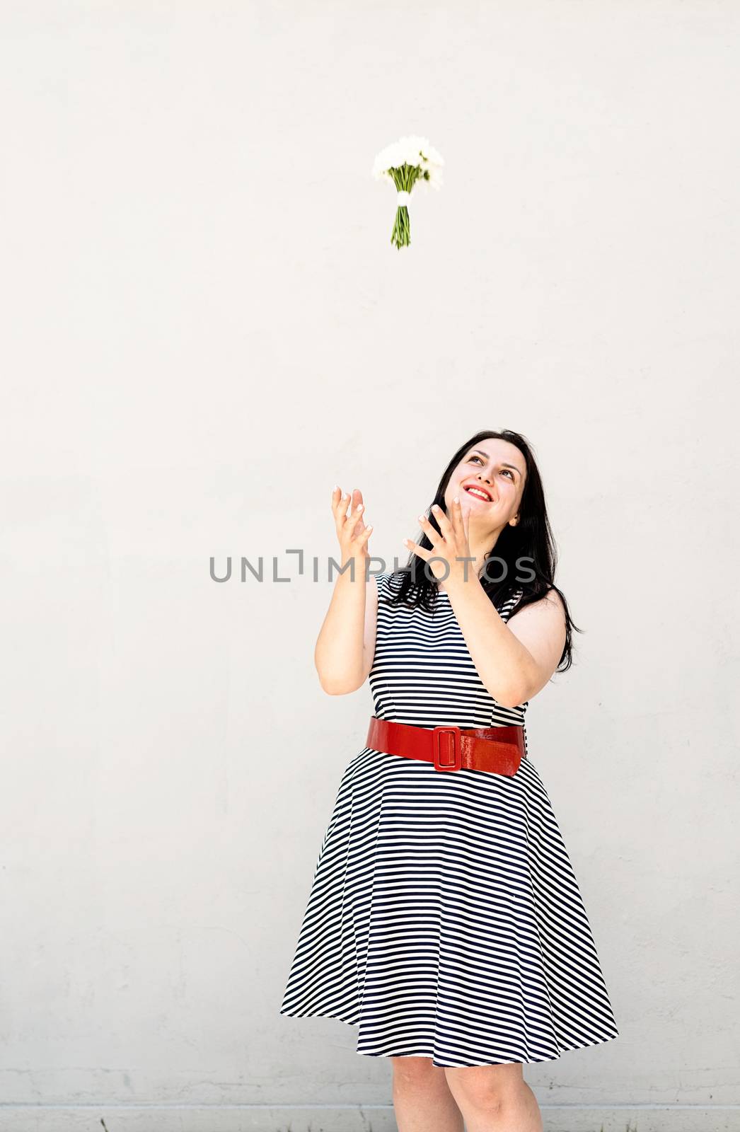 Happy young woman thowing a bouquet of flowers into the air by Desperada