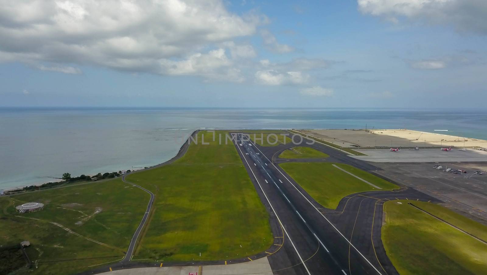 Runway at Denpasar International Airport in Bali, Indonesia. Runway reaching into the ocean. Aerial view to Ngurah Rai airport.