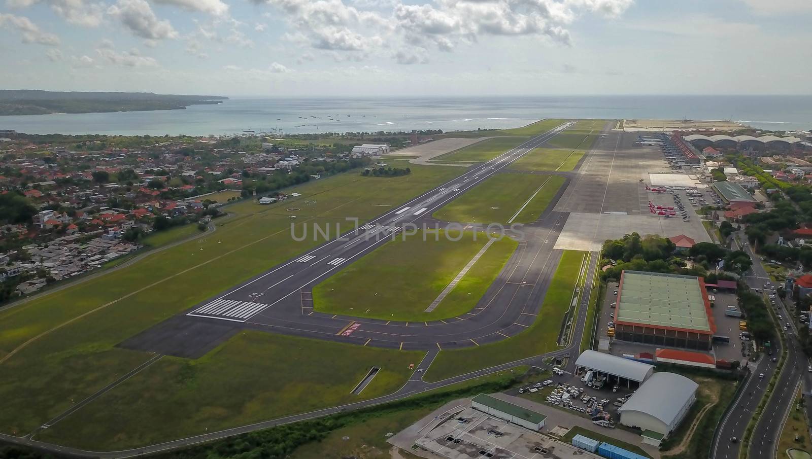 A view of Bali island after aircraft has been taken off from Ngurah Rai International airport. Runway reaching into the ocean. Aerial view to international airport in Denpasar.