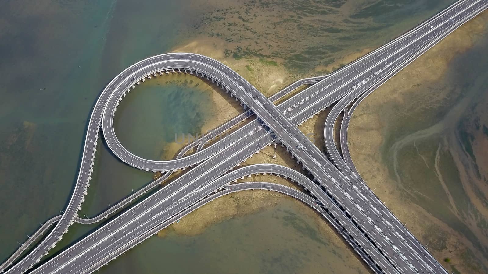 Aerial view to ring road toll way structure and construction from aerial view, nature and urban landscape of Bali before landing at the airport.