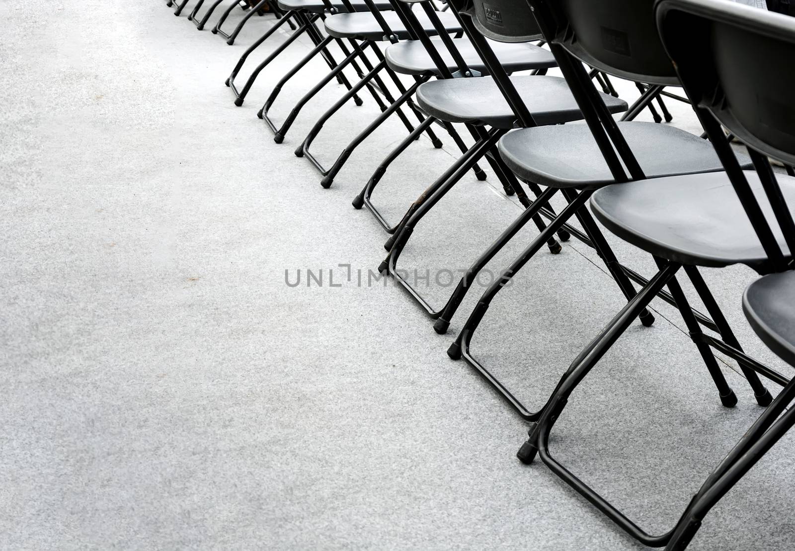 a group of empty folding chairs arranged in a row in a conference room. by rarrarorro