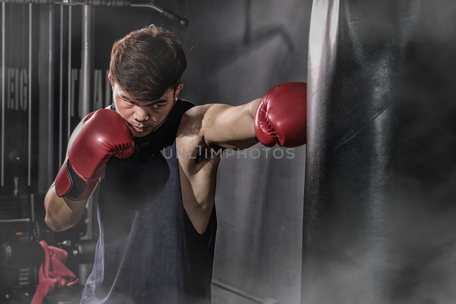 Boxer hitting a huge punching bag at a boxing studio by Surasak
