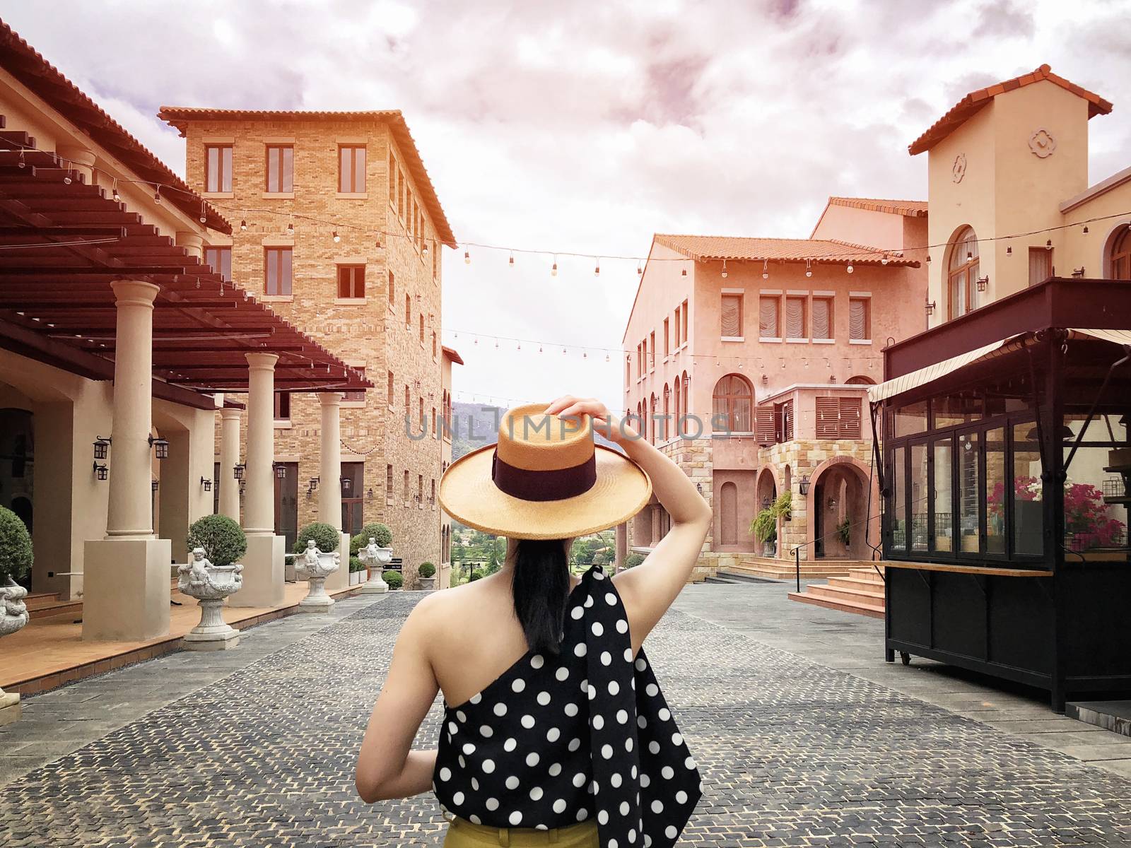 Woman wearing a planter panama hat visiting an Italian style village in summer