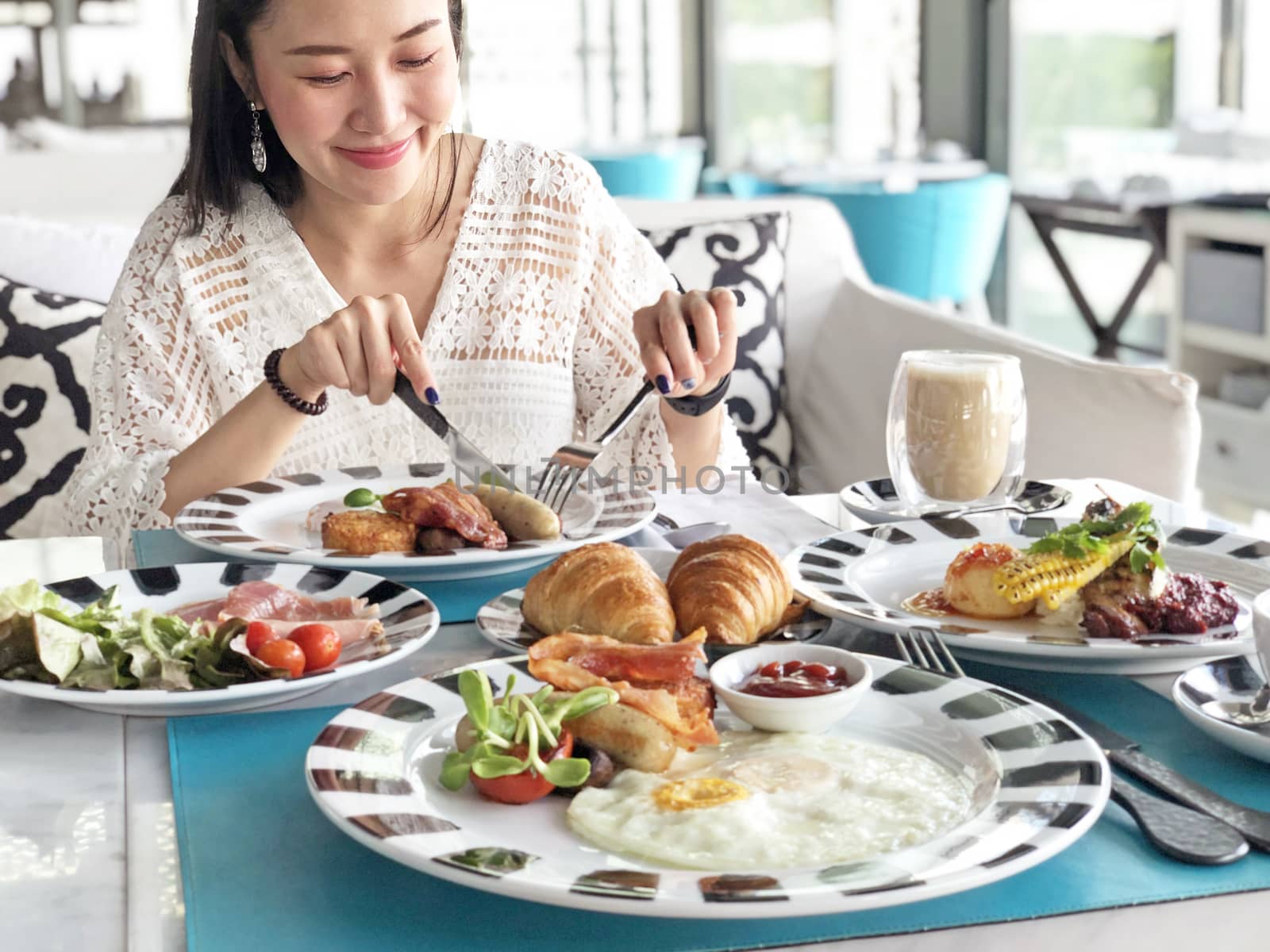 Young woman having healthy breakfast - fried egg, beans, salad,  by Surasak