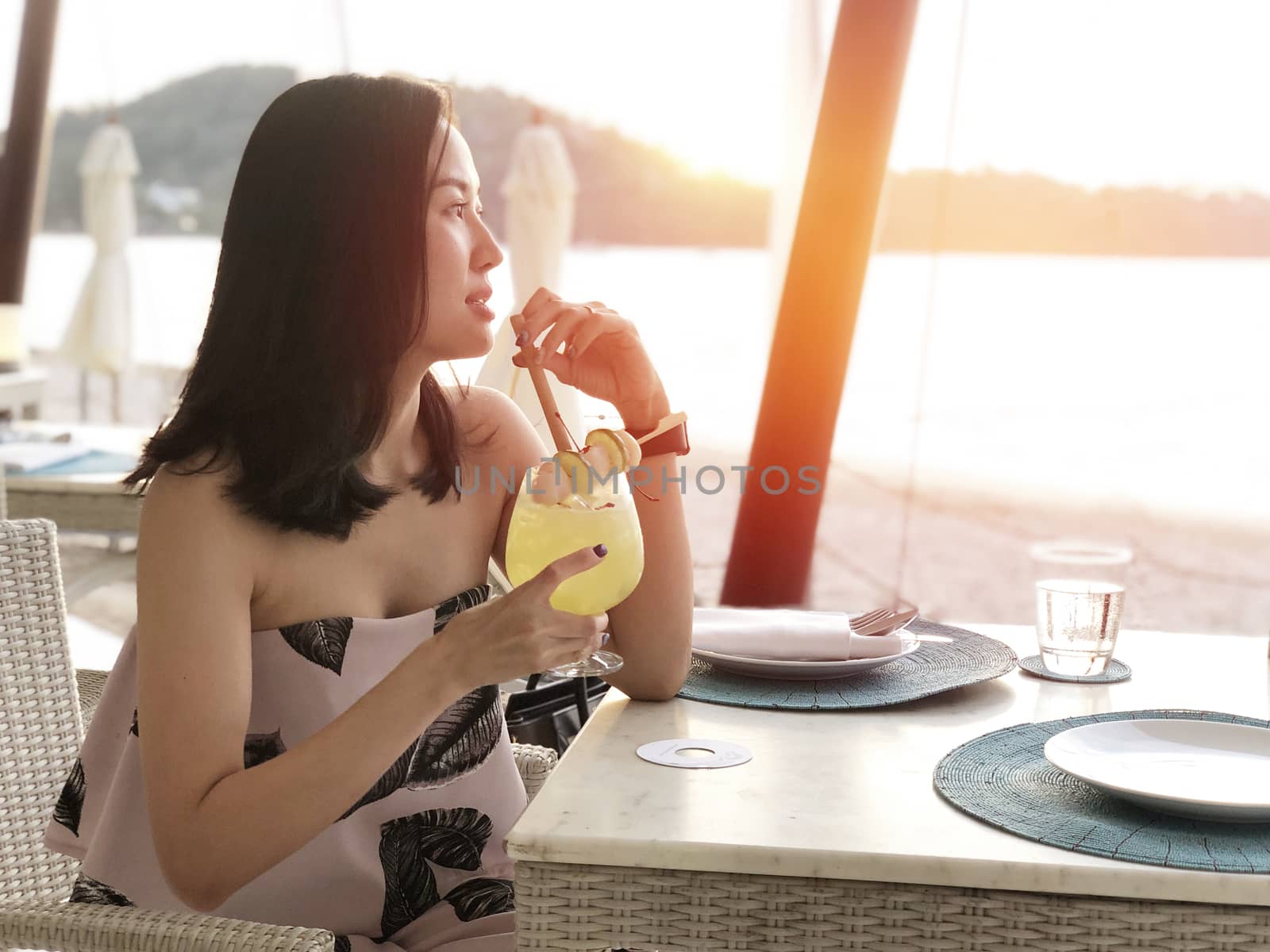 Beautiful woman holding a fruit cocktail on a tropical beach at  by Surasak