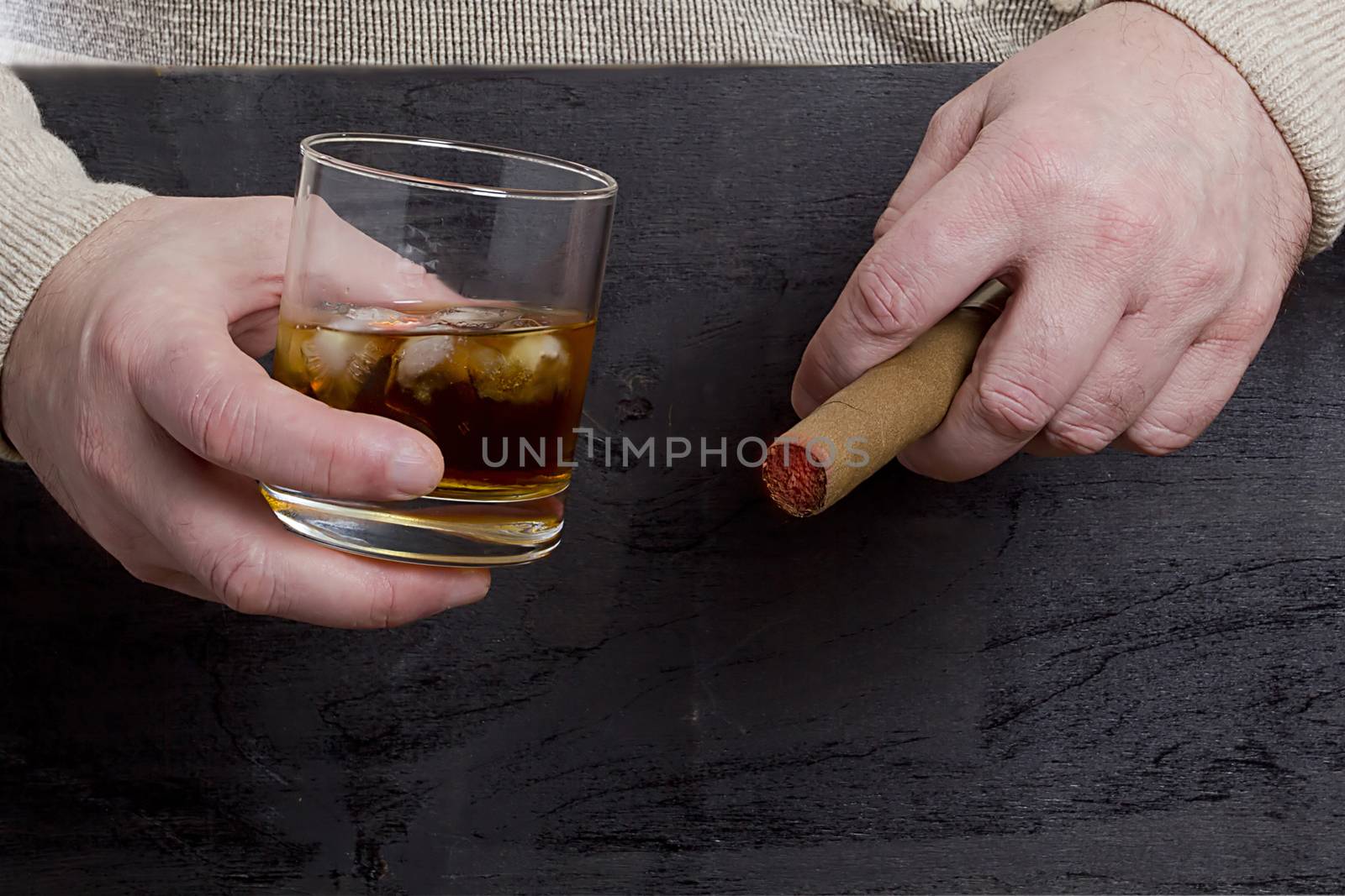 Men's hands with a cigar and a glass of whiskey