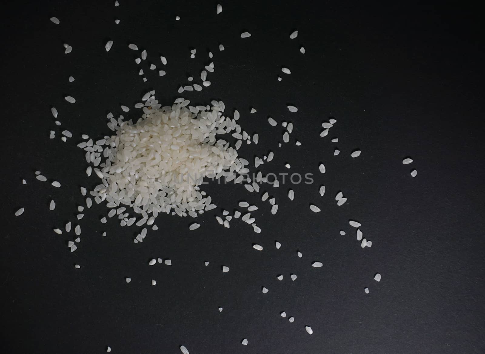 Scattered white uncooked rice on a black background