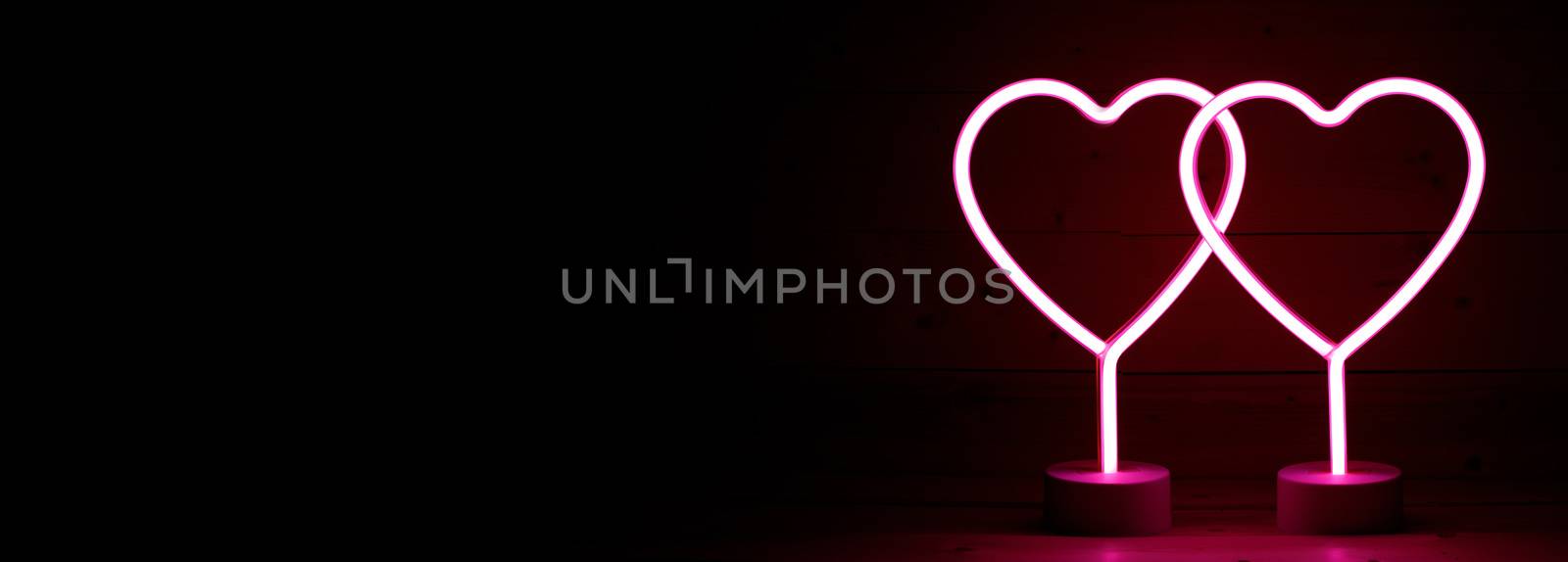 Two glowing pink neon hearts Valentines day party concept