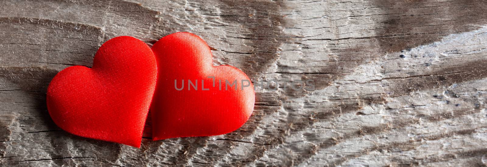 Valentine's day two red silk hearts on wooden background, love concept