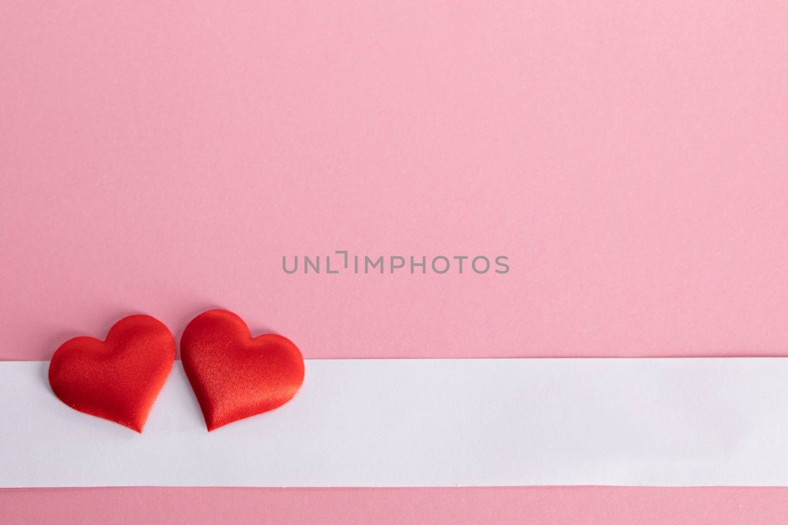 Valentine's day two red silk hearts and white paper on pink paper background, love concept