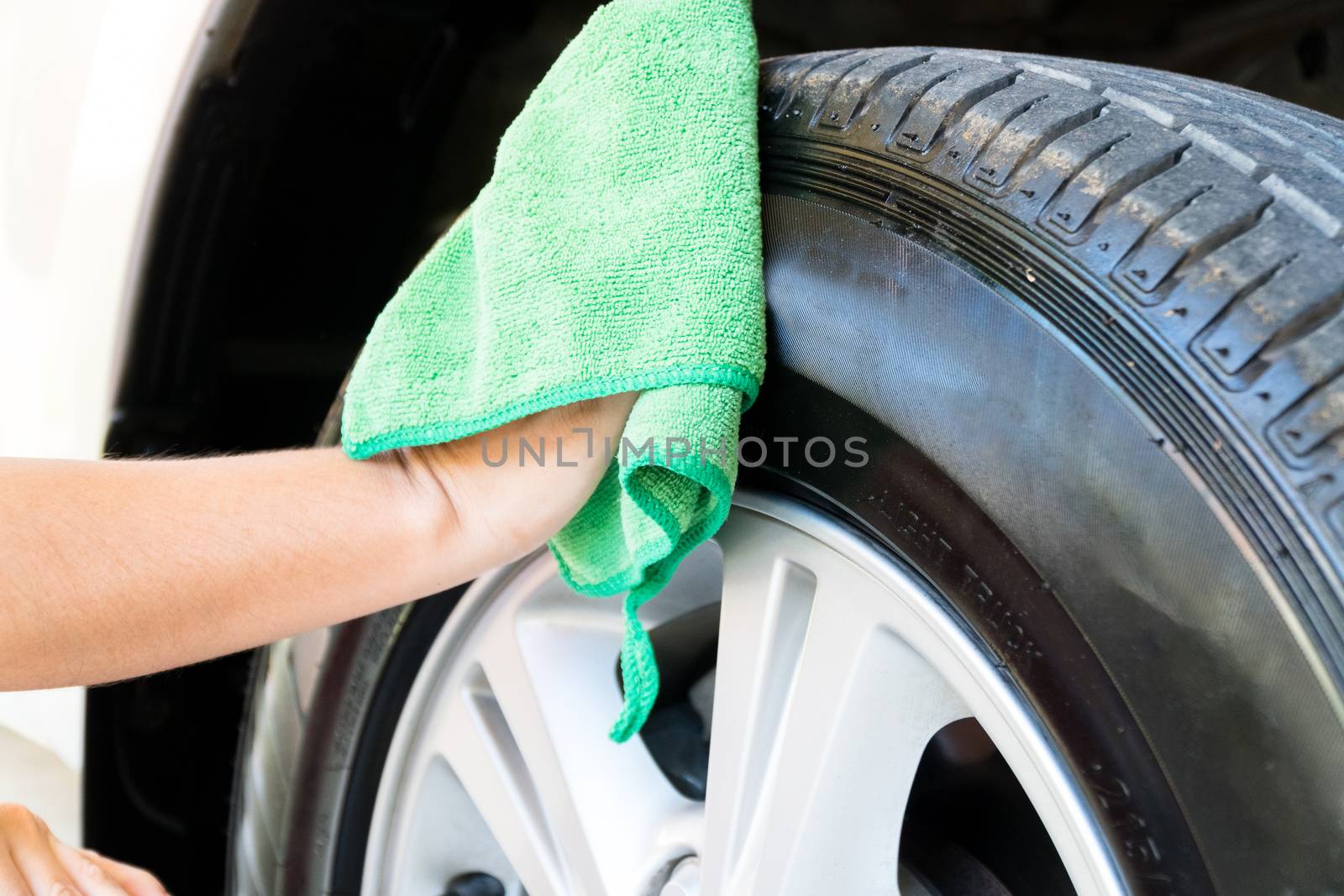 Women are wiping the car wheel with green textile