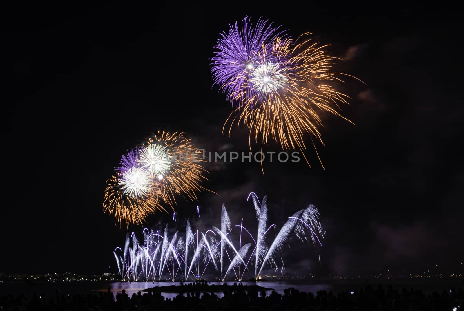 Scenic fireworks glowing in the night for the 14th of July celebrations in the harbor of Cannes, Cote d'Azur, France