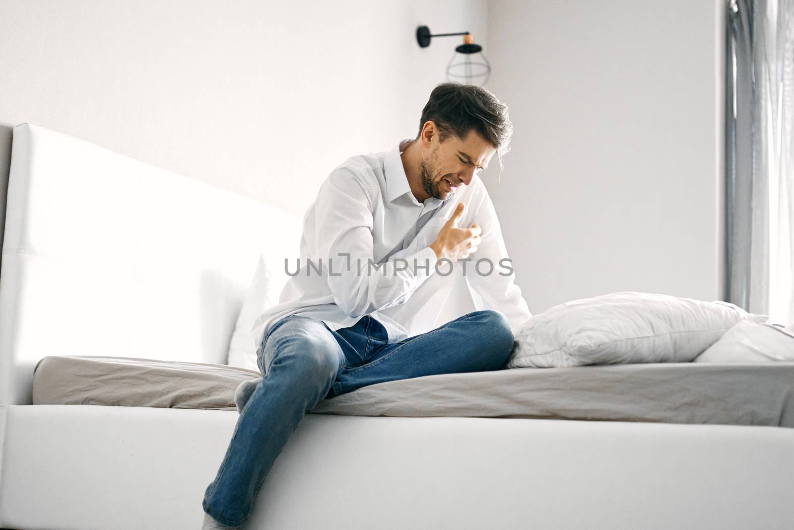 Lonely man crying on the bed indoors in full growth