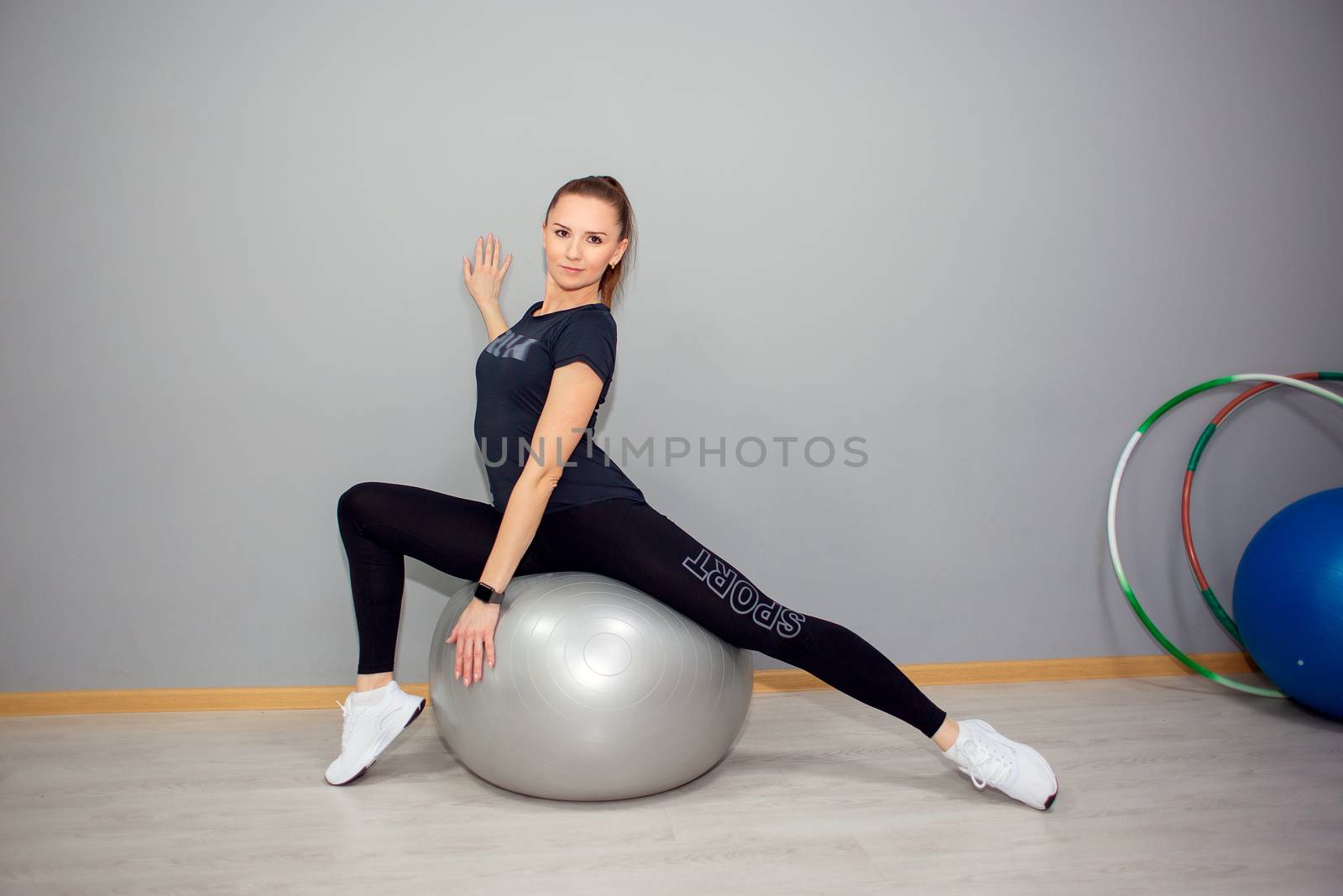 Beautiful young athletic woman posing while sitting on a big fitness ball by borisenkoket
