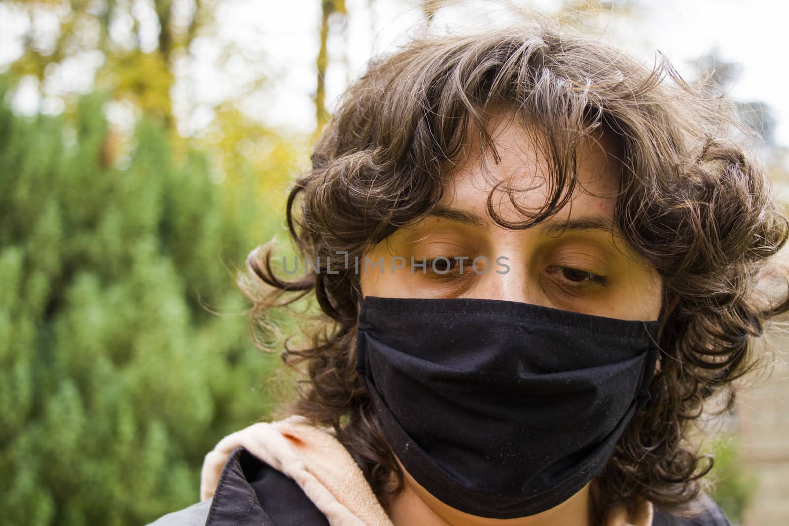 Woman's portrait with black medical face mask, nature background