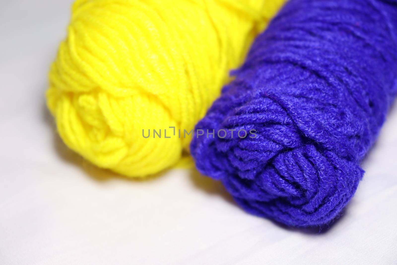 blue and yellow colored yarn closeup on white background