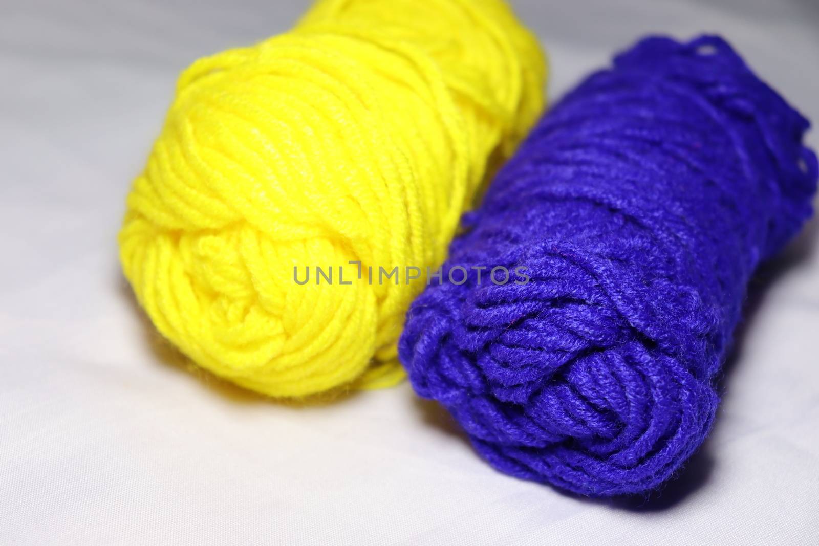 blue and yellow colored yarn closeup on white background