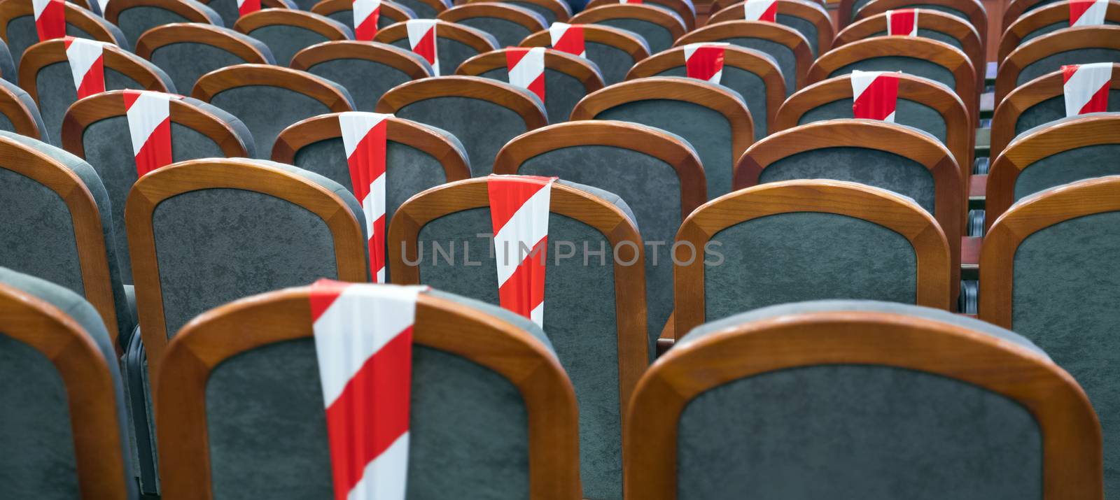 Background of empty seats in the cinema, theater, auditorium with a warning label. Presentation of a conference, opera, theatrical performance. Work during coronavirus, adhering to social distancing by synel