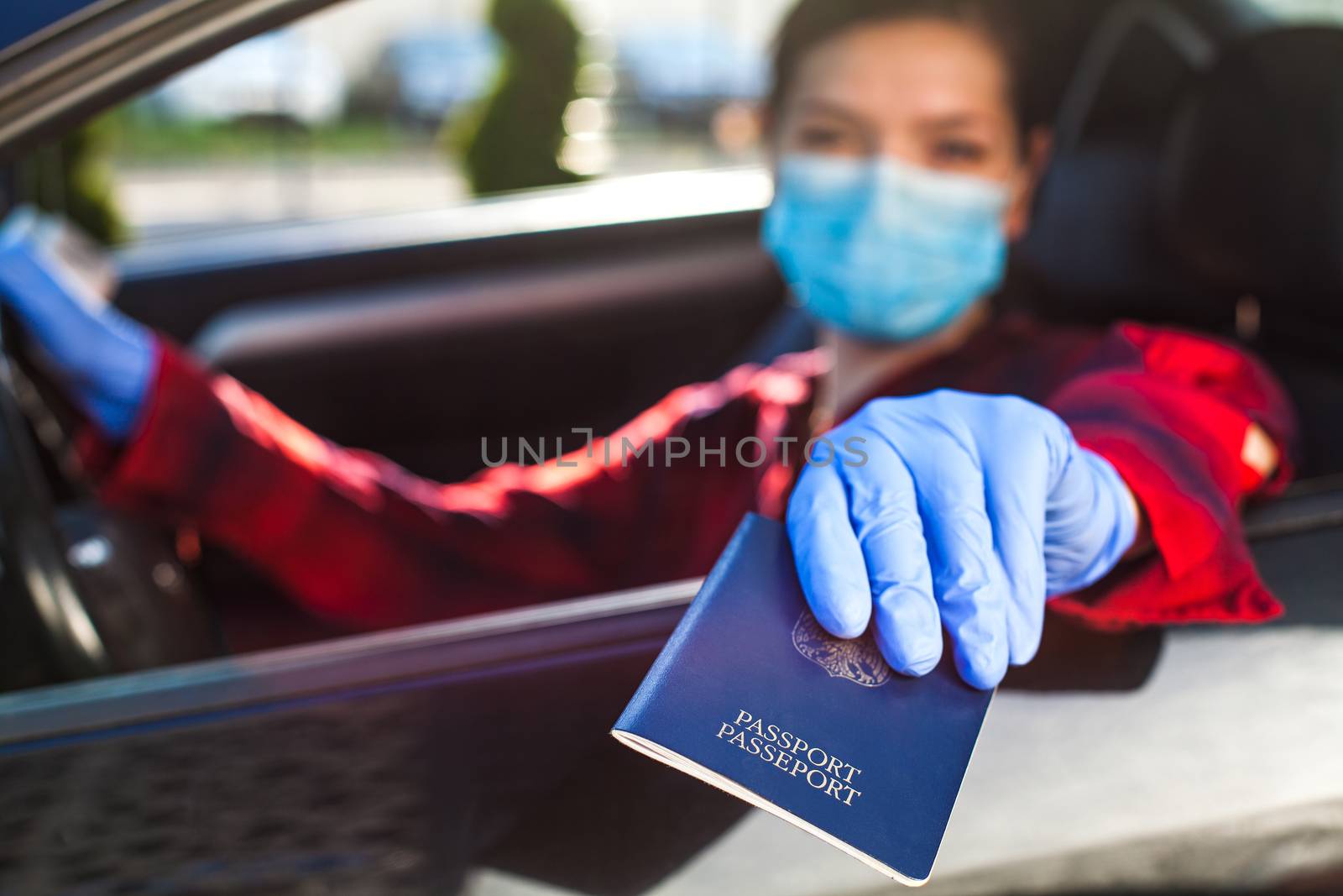 Young woman holding blue passport through car window,patrol border security staff checkpoint control,Coronavirus immunity card health passport,safety and protection from spread and transfer of virus