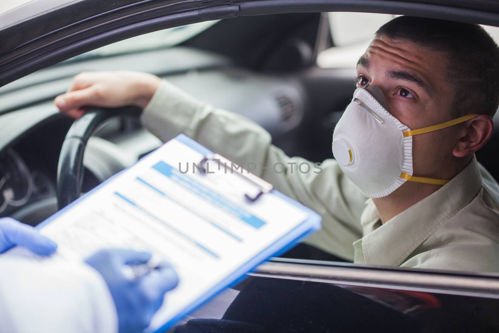 Young man wearing protective face mask in drive-thru Coronavirus car testing center,answering health check questionnaire,doctor or paramedic performing US point of care COVID19 test,rt-PCR diagnostic 