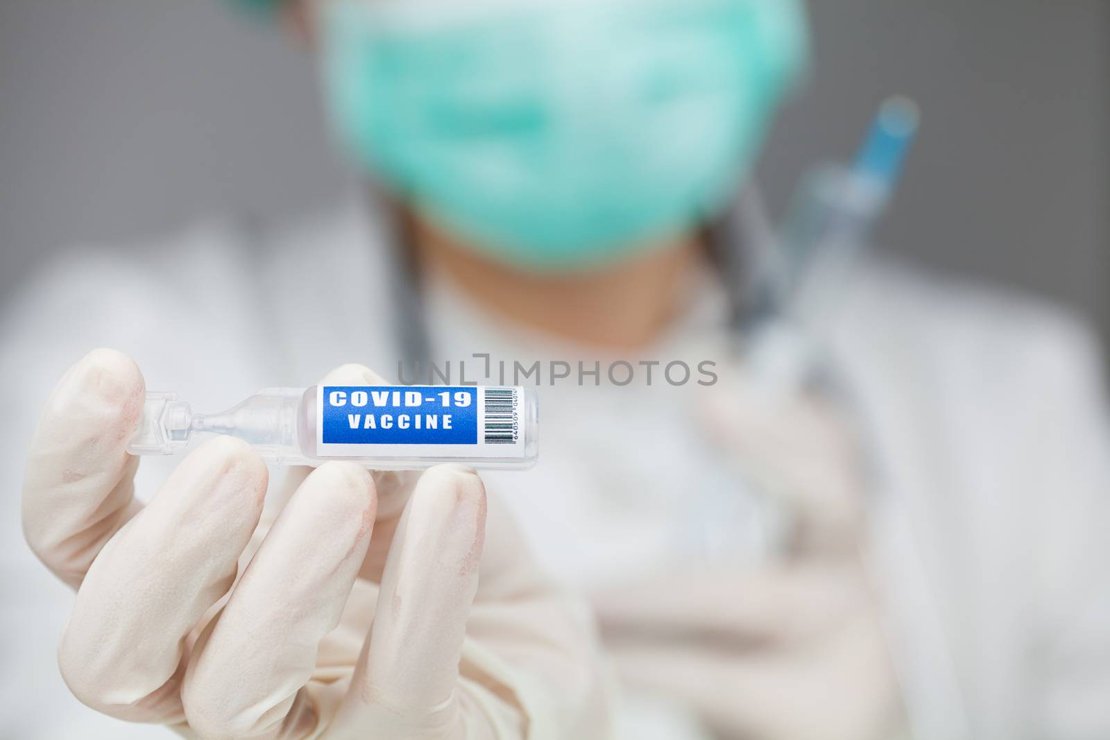 Scientist or doctor holding a vaccine ampoule injection by Plyushkin