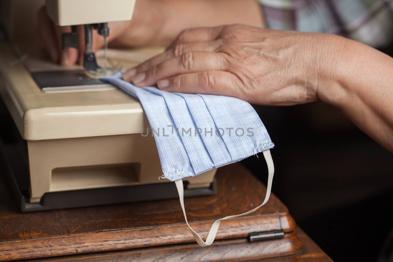 Woman hand sewing face mask by Plyushkin