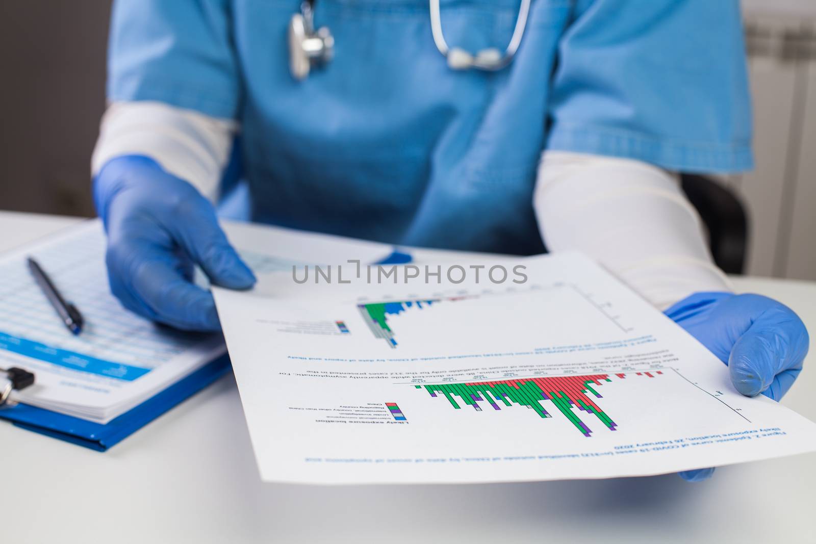 Doctor wearing protective gloves holding document chart by Plyushkin