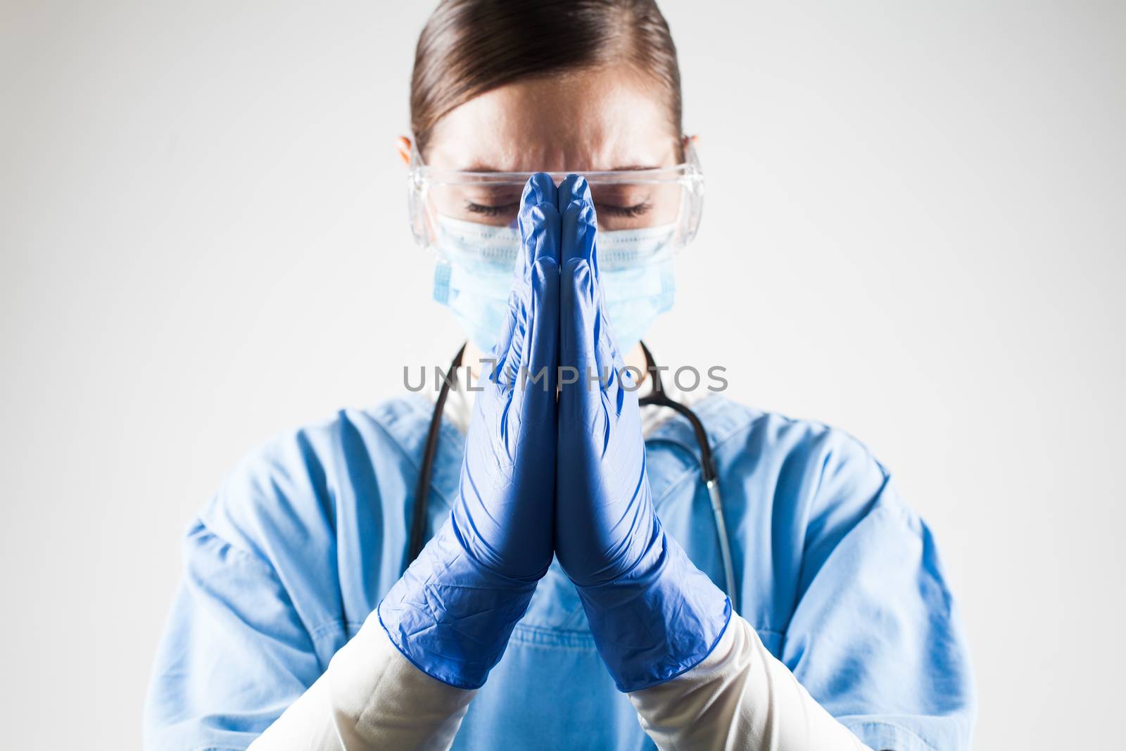 Female doctor praying hands gesture,hope and belief amid worldwide Coronavirus COVID-19 virus disease pandemic crisis outbreak,high global patient death toll and mortality rate with numerous victims