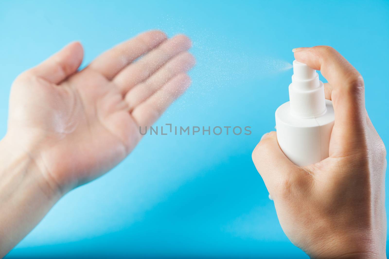 Female caucasian hands spraying antibacterial alcohol sanitizer by Plyushkin