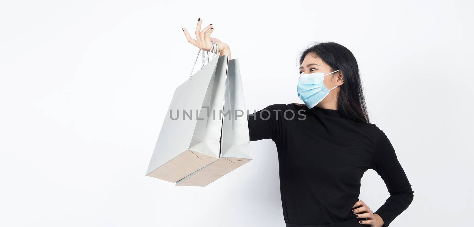 Asian woman holding shopping bags in her hand and wearing medica by gnepphoto