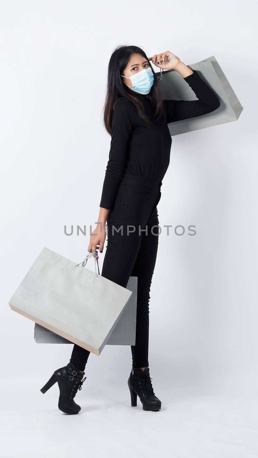 Asian woman holding shopping bags in her hand and wearing medica by gnepphoto