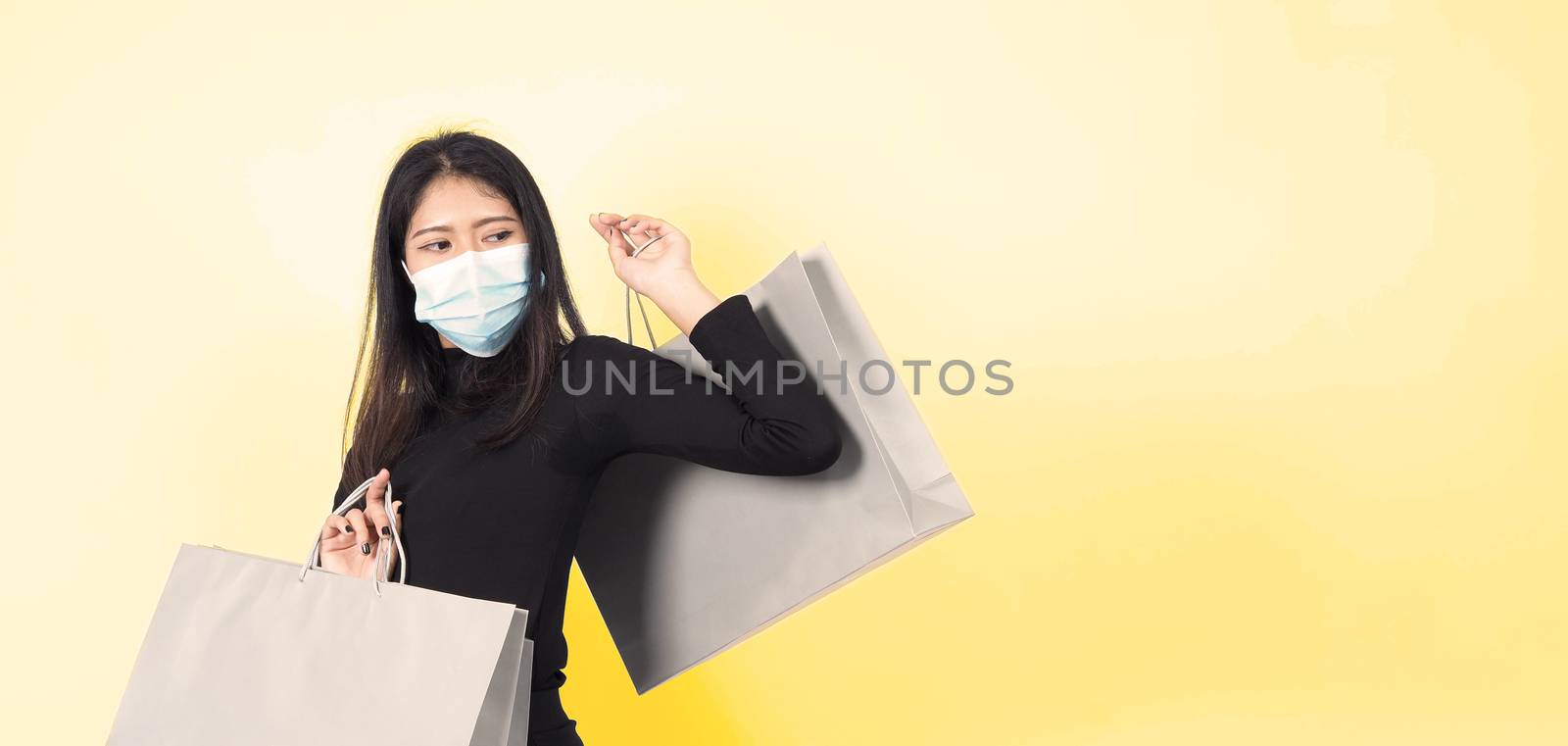 Asian woman holding shopping bags in her hand and wearing medica by gnepphoto