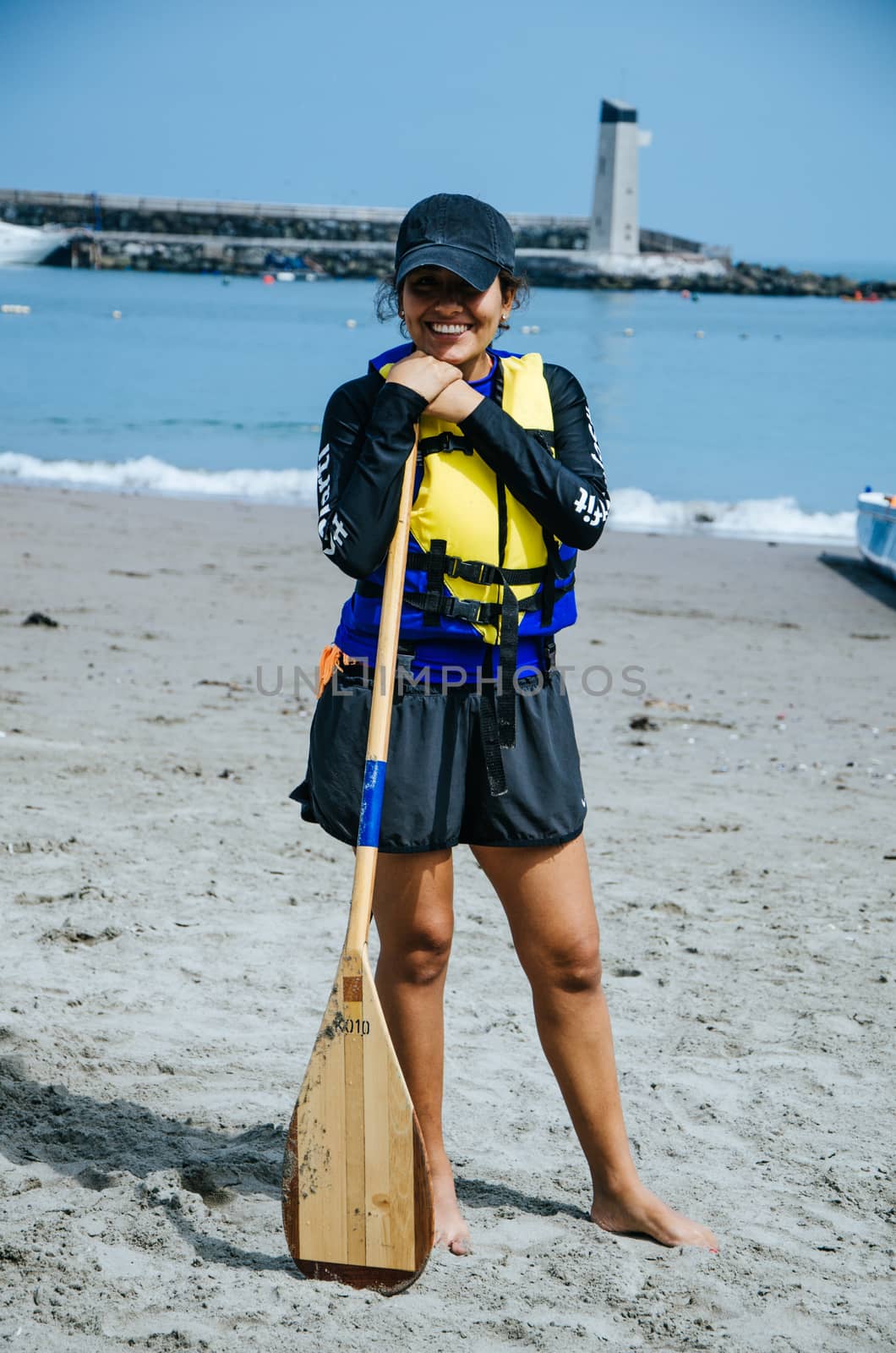 Young woman paddler smiling with an oar in hand at the seashore